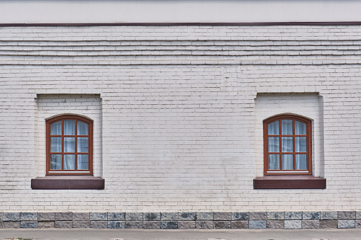 Two windows on a white brick wall of a historical building of the 18th century. Architecture concept