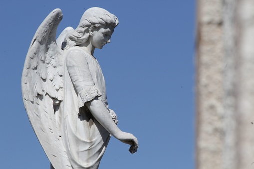 Guadalajara, Mexico – July 24, 2019: A beautiful angelic statue stands against a bright blue sky in a peaceful cemetery setting