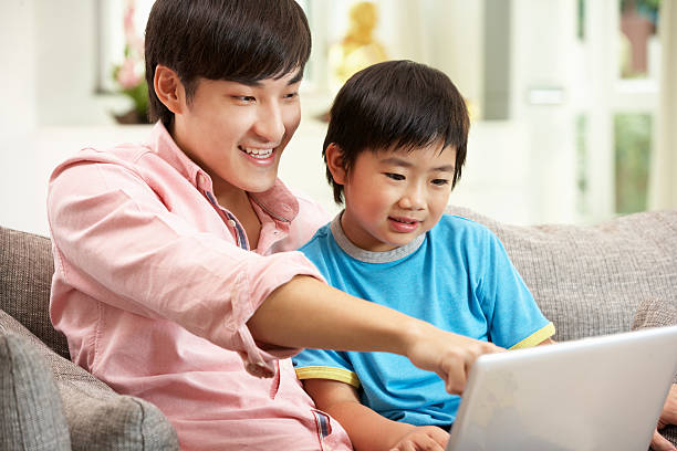 istock Chinese Father And Son Using Laptop Whilst Relaxing On Sofa 153098934