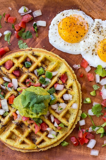 A top view of a savory waffle with eggs.