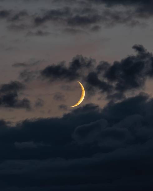 istock Large half-moon with wispy dark clouds in the sky at night 1531009456