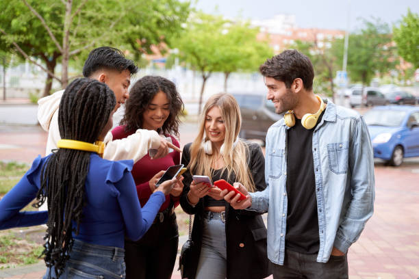 istock Group of friends looking at their mobile phones while standing outdoors together. 1531013362