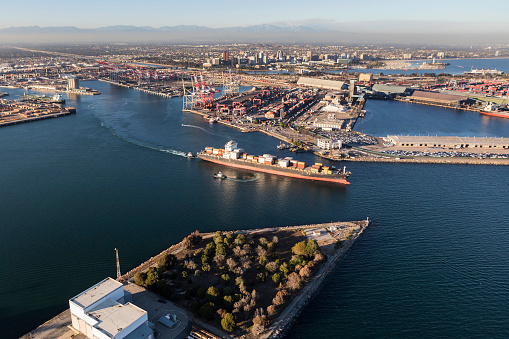 Aerial view of container cargo ship leaving Long Beach Harbor in Los Angeles County California.