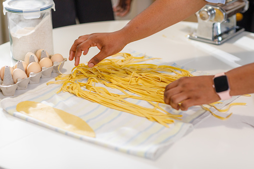 Shot of young woman's hands spreading uncooked pasta on the table.