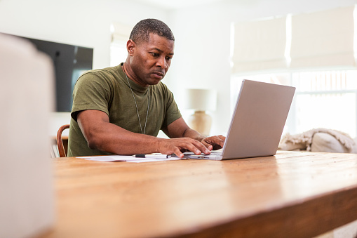 Sitting at his dining room table, the mature adult soldier takes continuing education courses from a local university online.