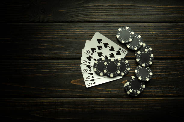 istock Playing poker with a winning straight flush combination. Cards with chips on a black vintage table in a poker club. Copy space 1531064683