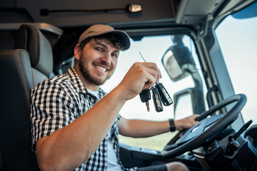 Happy man holding truck keys and smiling to be the owner.