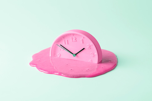 The pink clock melts against the birch background. Creative concept of time.