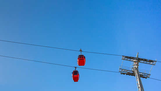 Two red cabins of the cableway against the blue sky.