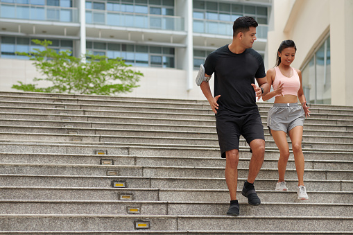 Fit young boyfriend and girlfriend running down stairs to engage more leg muscles