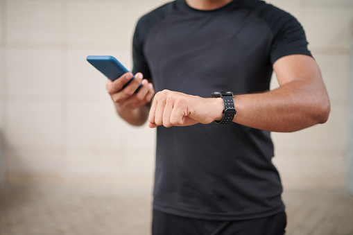 Sportsman checking notifications on smartwatch and smartphone after workout