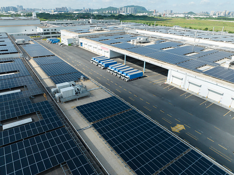 Aerial view of solar panels on the roof of a large storage facility, factory. Providing electricity for the facility, self sufficient facility. Solar panel installation on the roof of a factory.