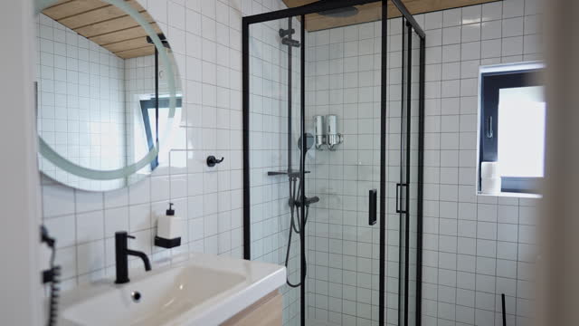 Neat white bathroom with shower cabin indoors. No people inside in summer house on tourist resort.