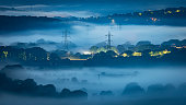 Misty valley at night, showing electricity pylons
