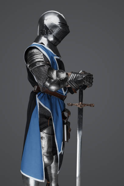 istock Medieval guard dressed in armor and blue surcoat holding a sword 1531148245