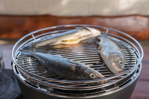 Close up of three sea basses on the grill cooked outdoors.