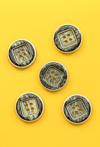 istock Grey plastic buttons on a yellow background. Sewing tools. Top view. Copy space. 1531180235