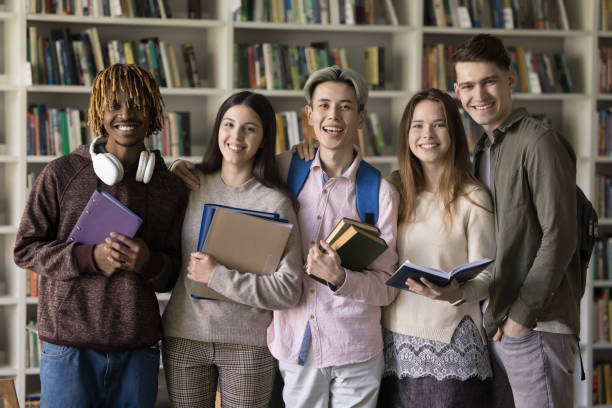 istock Attractive multiracial schoolmates posing in school library 1531183513