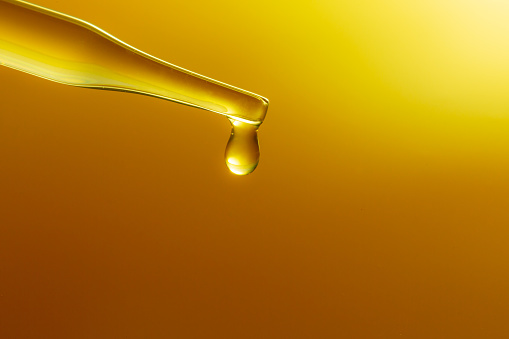 Yellow science test tube,Dropping yellow chemical liquid or essential oil to test tube on white background, lab research and development concept