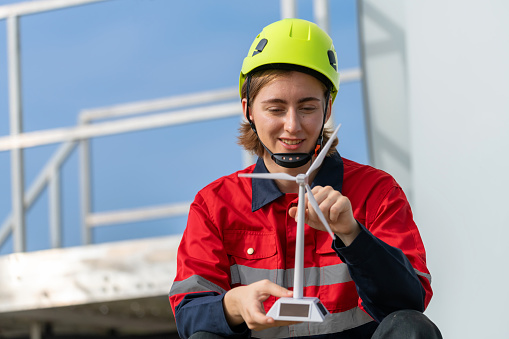 Engineer analyzing wind turbine model and assessing structure while turning the paddle. Confident and focused demeanor reflects their expertise and dedication to the field. The concept of technology-driven sustainable energy generation.