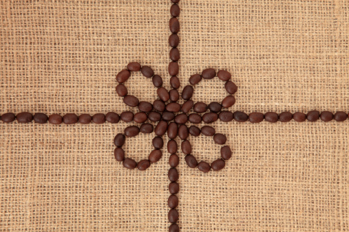 Coffee bean abstract design over hessian background.