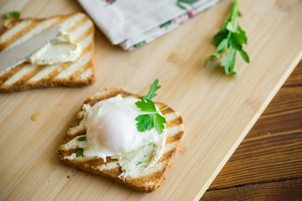 Fried toast bread with spread and poached egg, on a wooden table. Quick breakfast.