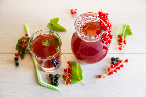 fresh berry juice from red and black currant, on a light wooden table