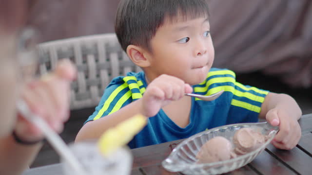Little boy is enjoying a chocolate ice cream at the restaurant.