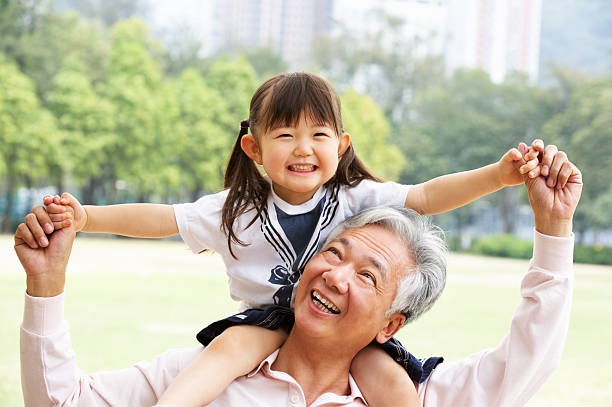 Chinese Grandfather Giving Granddaughter Ride On Shoulders Chinese Grandfather Giving Granddaughter Ride On Shoulders In Park china chinese ethnicity smiling grandparent stock pictures, royalty-free photos & images