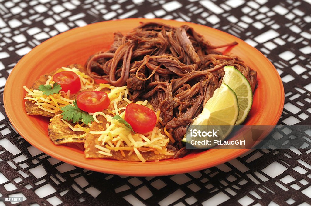 Spicy beef dinner and nachos Spicy shredded beef with cheesy nachos on an orange plate with a geometric background Barbecue - Meal Stock Photo