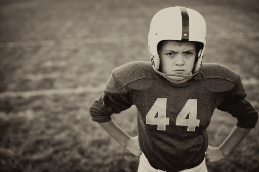 A vintage American football player stands strong and tall. Just try and run past him.