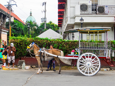 Manila, Philippines - February 18, 2023: Picturesque street in the old town with horse carriage.