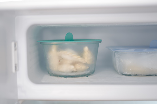 Frozen food in glass containers in small fridge. Compact kitchen space. Cold temperatures for food. Organize homemade meal