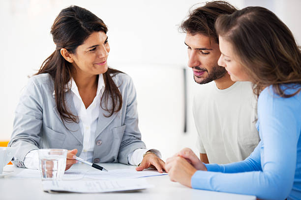 Couple meeting with financial advisor Financial consultant presents bank investments to a young couple. Taken at iStockalypse Milan.   mortgage document photos stock pictures, royalty-free photos & images
