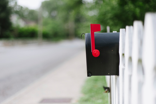 Mailbox on white fence.