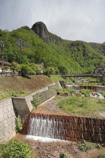 Sounkyo, Japan - May 31, 2023: The Kurodakesawa River flows toward the Ishikari River in the Sounkyo Onsen resort town in the Daisetsuzan National Park. Spring afternoon in the Kamikawa District of central Hokkaido.