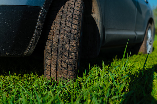 Dirty car wheel on green grass, close-up view