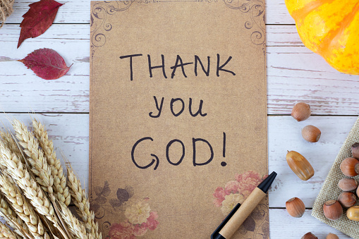 Thank You God, handwritten message on vintage paper with autumn leaves, pumpkin, and ripe wheat stalks on wood. Top table view. Christian thanksgiving, gratitude, blessing, and praise to Jesus Christ.