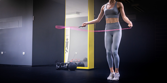 Young woman exercising on jump rope in fitness studio.