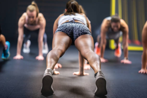 Rear view of a young female instructor and a group of young women attending cardio class.