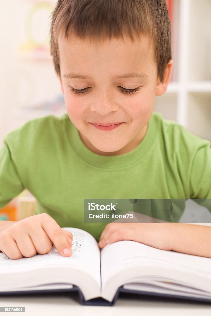 Boy practice reading at home Boy practice reading at home following text with finger Book Stock Photo