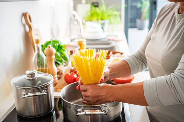 istock Woman holding uncooked spaghetti in a cooking pan 1531472596