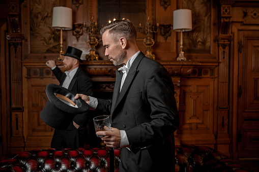Two handsome 1920s style gentlemen in a luxury brown bar