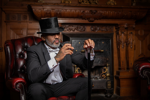 A handsome elegant 1920s style black gentleman in a luxury drawing room with a chesterfield sofa