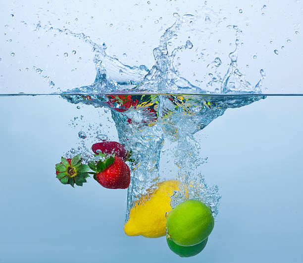 Strawberries, lemon and limes splashing in water stock photo