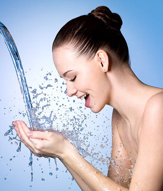 istock Happy woman washing face under water 153150104