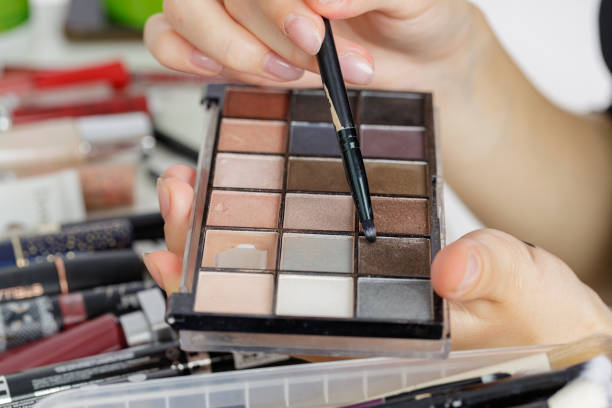 istock cosmetic scene with make up brushes, eye shadows palette, lipstick and hands 1531508950