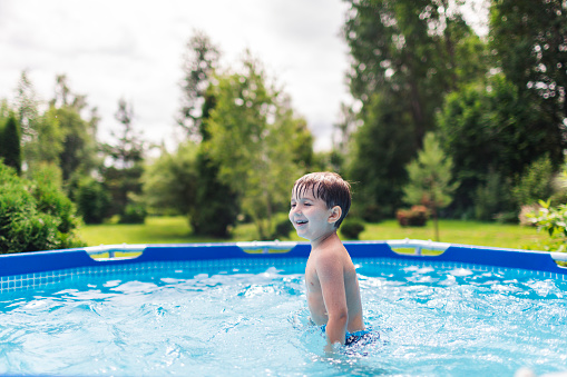 Child playing in backyard in swimming pool