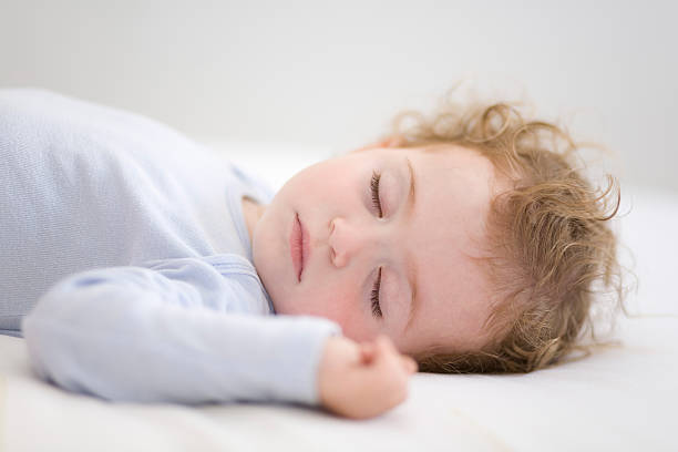 istock Sleeping baby in periwinkle bodysuit lying on white sheets 153151874
