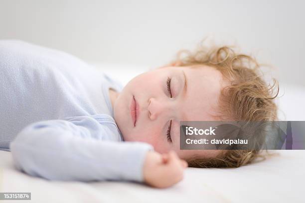 Sleeping Baby In Periwinkle Bodysuit Lying On White Sheets Stock Photo - Download Image Now
